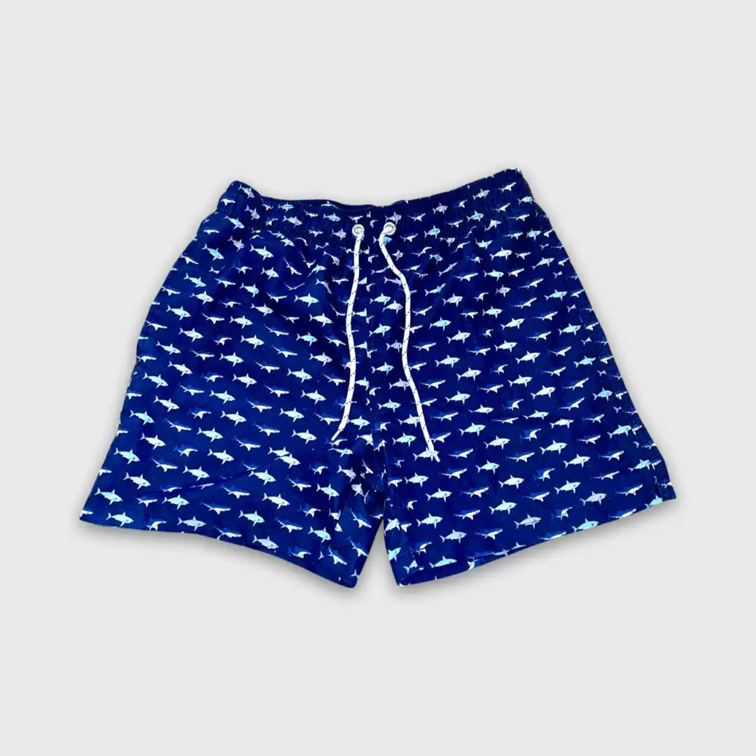 Navy blue swim shorts with a repeating white shark pattern and drawstring waist.